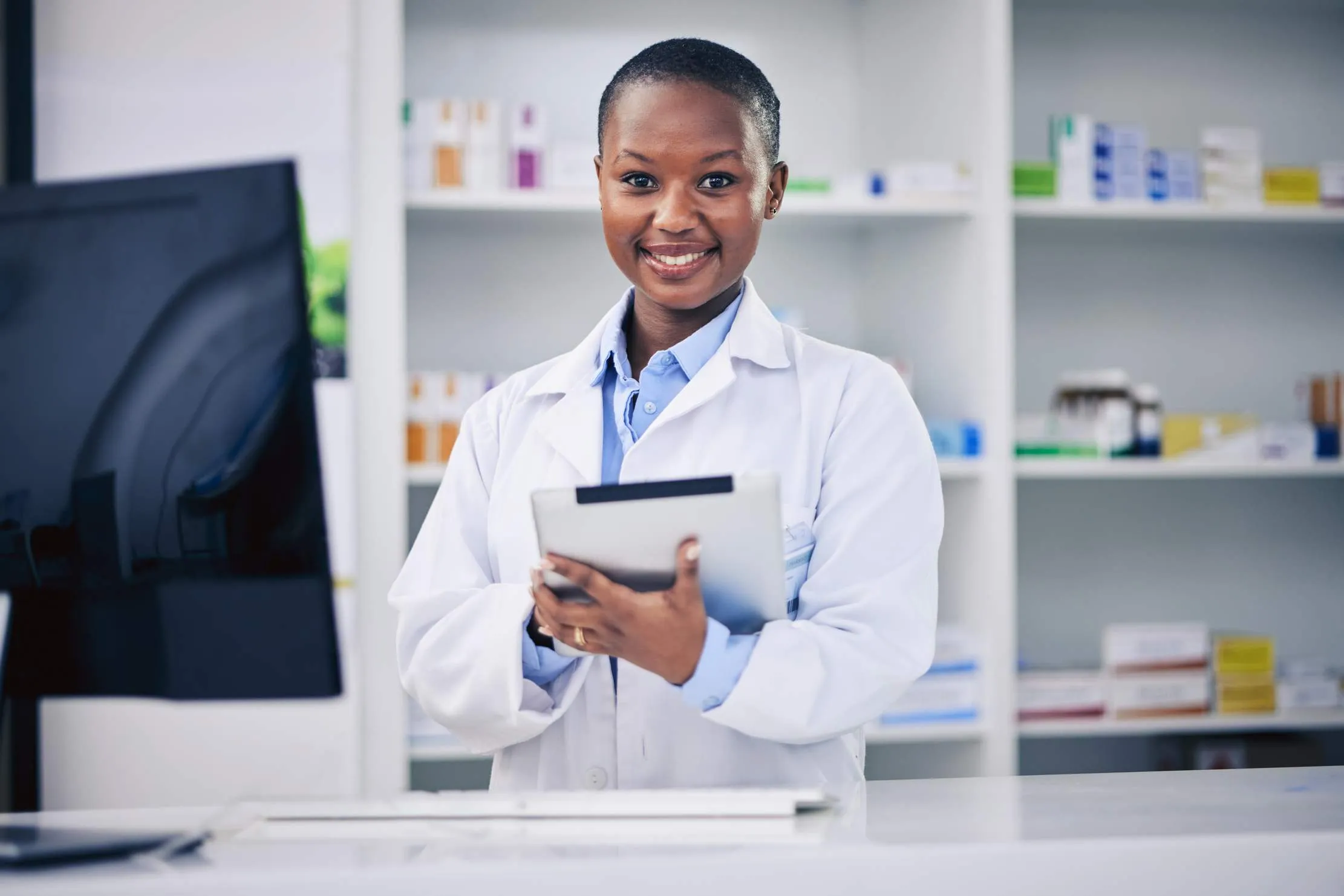 Pharmacist with a tablet checklist verifying medicine batches, lot numbers, and expiry dates at the drug store counter