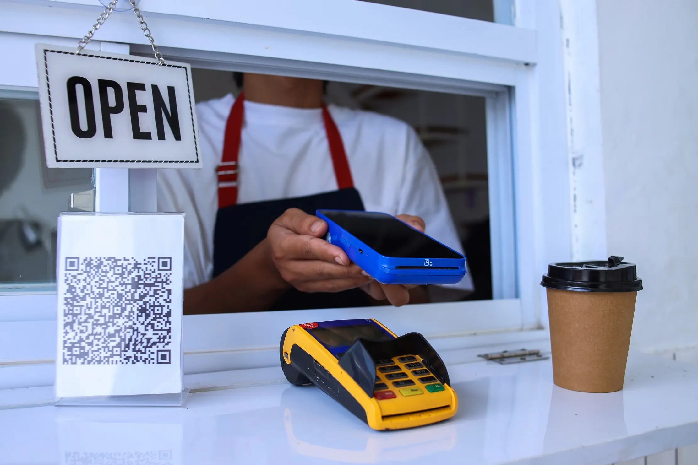 Café cashier holding a payment terminal at the counter