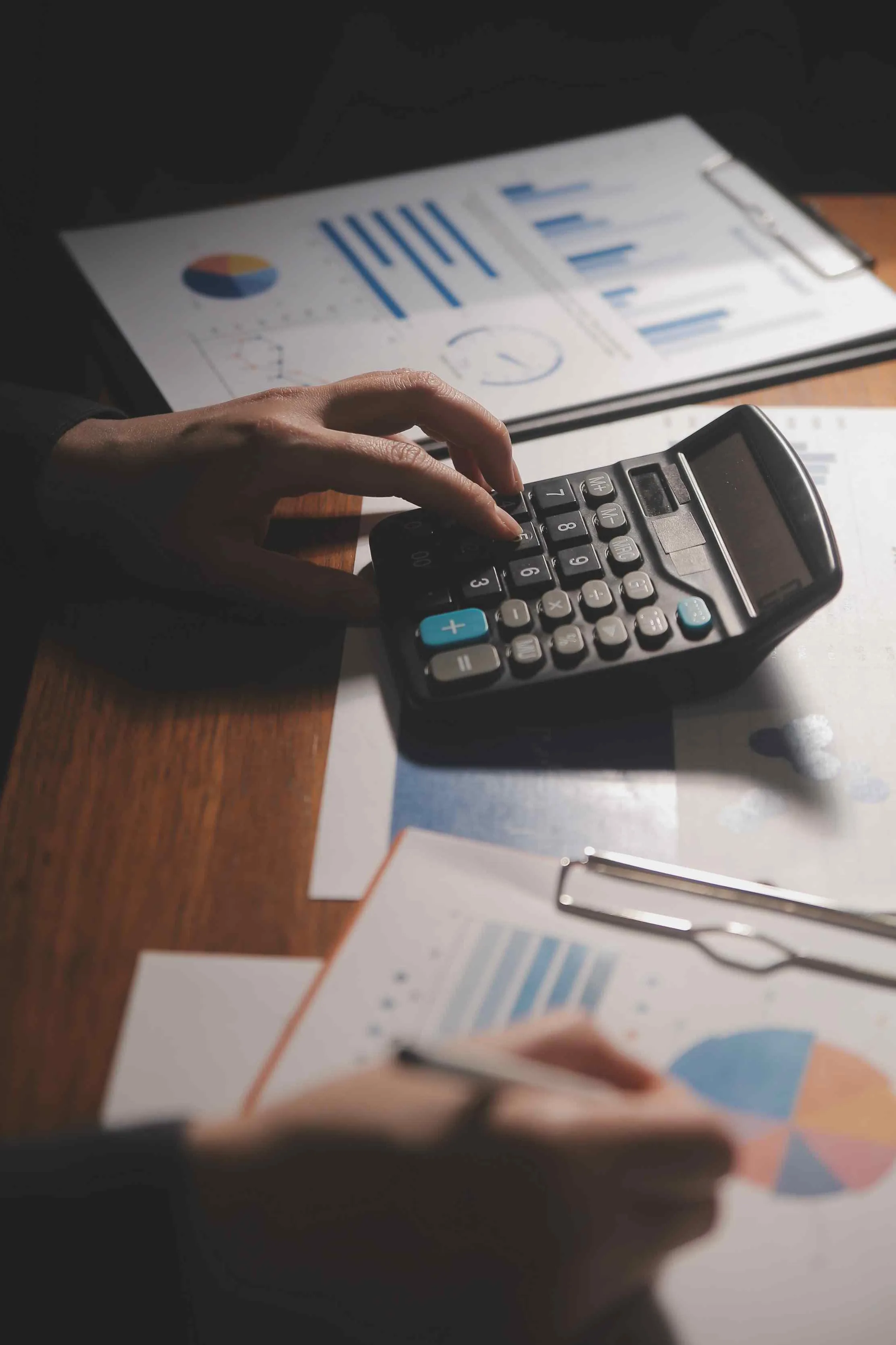 Business owner using a calculator and laptop for finance and accounting review
