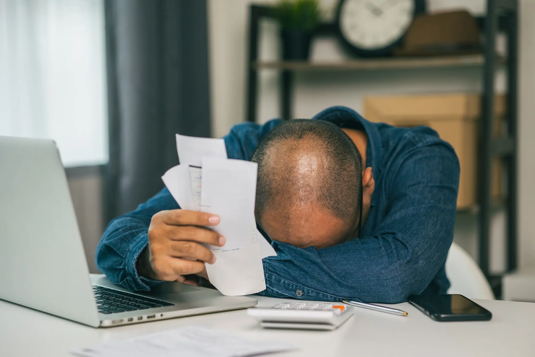 Client professionnel examinant des factures impayées près d’un ordinateur lors d’une relance