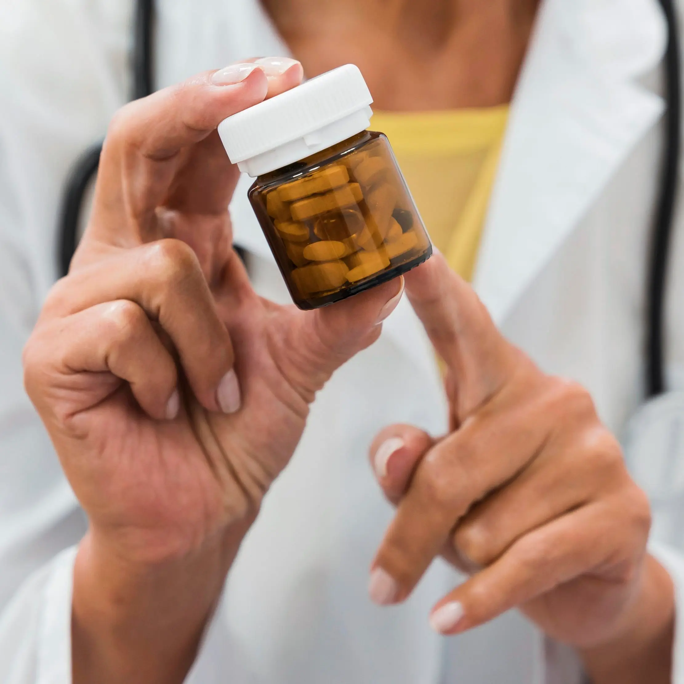 Person in a white coat examining a medicine bottle during a product check