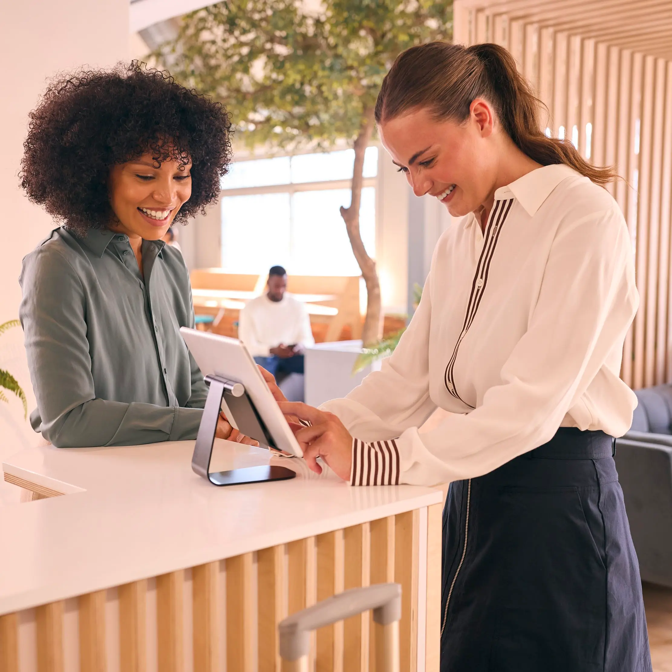 Personnel hôtelier utilisant une tablette à la réception, illustrant les opérations Maduuka pour les hôtels et les resorts