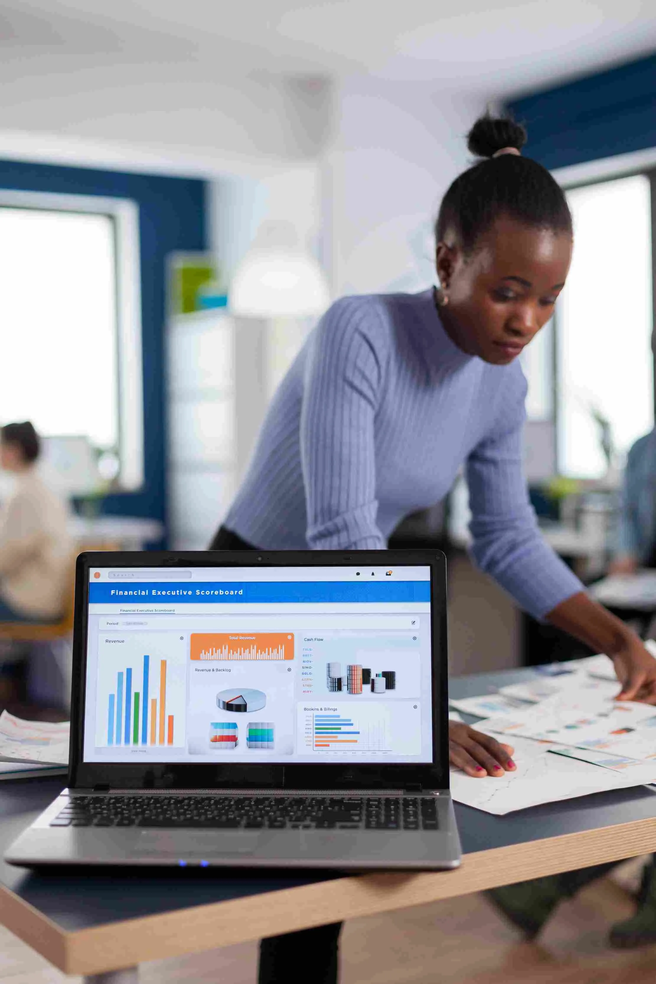 Dirigeante consultant graphiques et statistiques financieres sur un ordinateur portable, representant le reporting profits et pertes de Maduuka