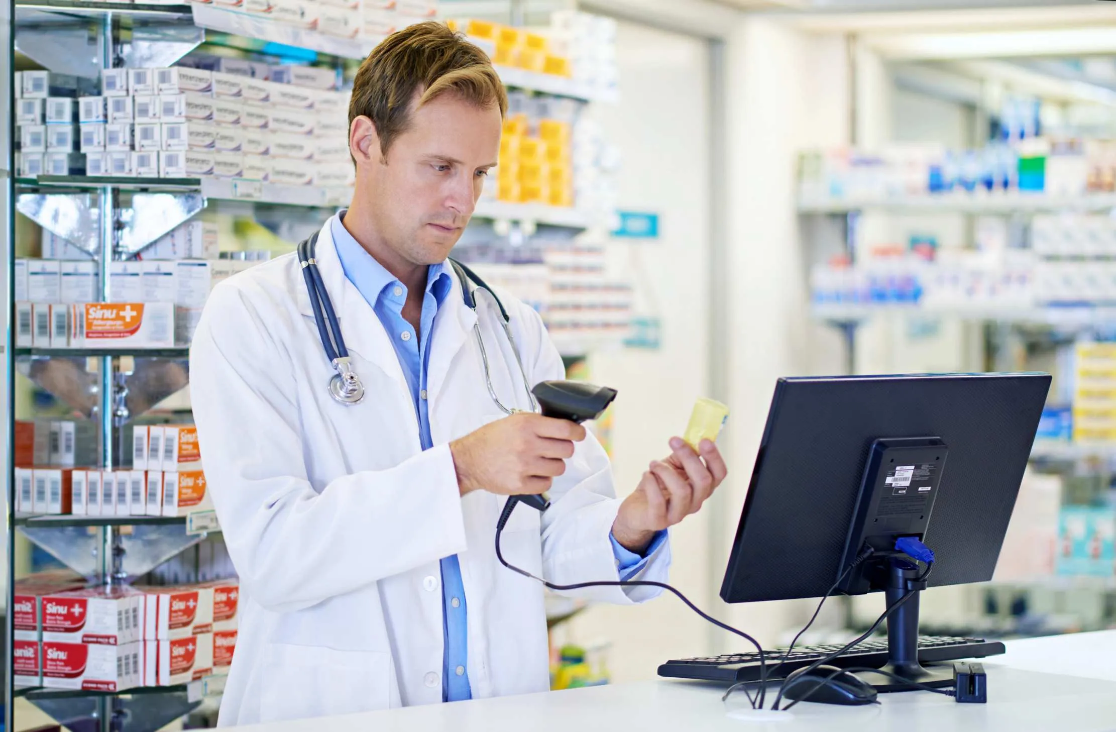 Pharmacist using a barcode scanner at a drug store POS to dispense medicine from a tracked batch — Maduuka pharmacy management software for FEFO batch and expiry control