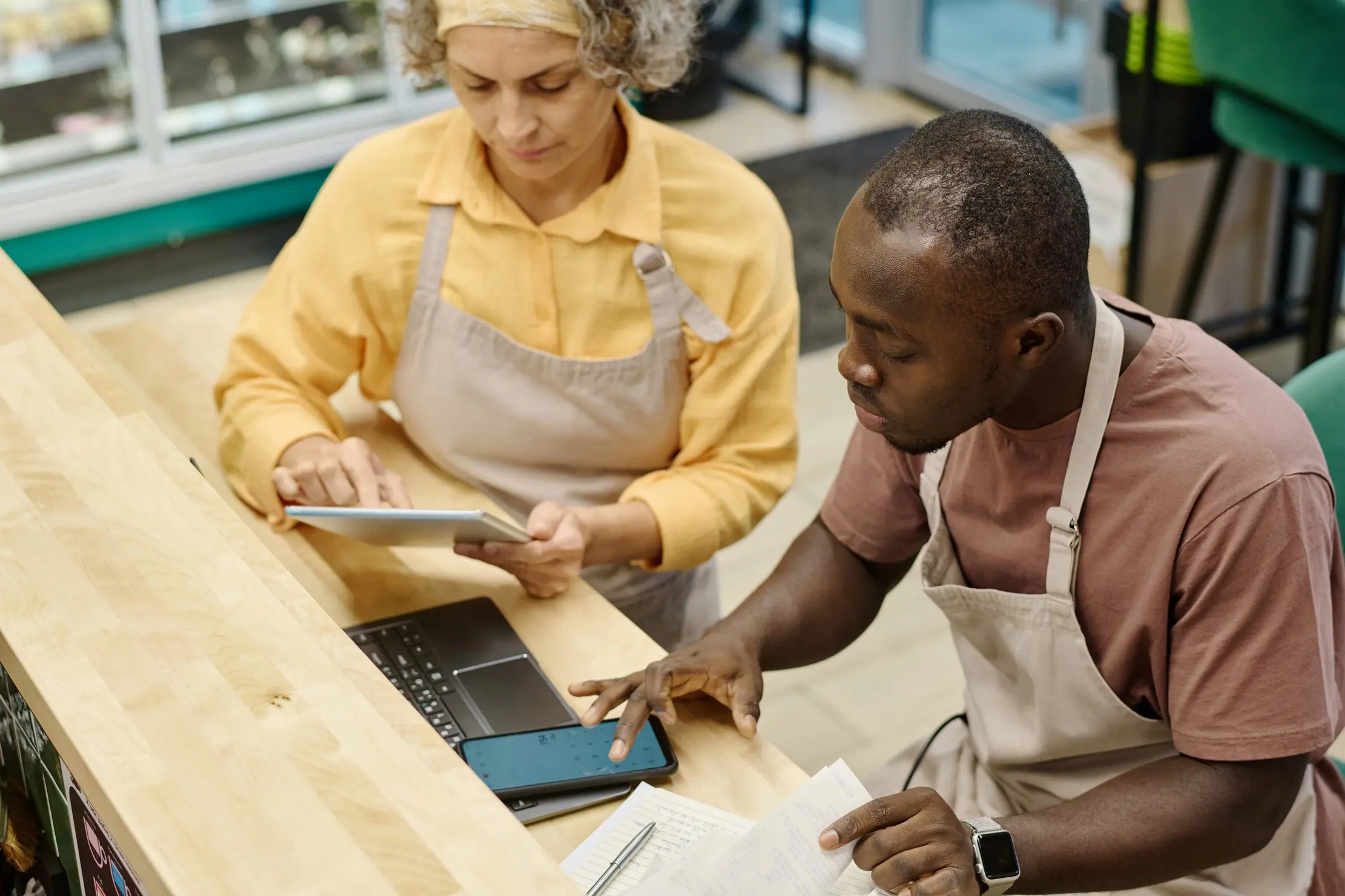 Store manager training an attendant on a retail computer before the sales queue forms