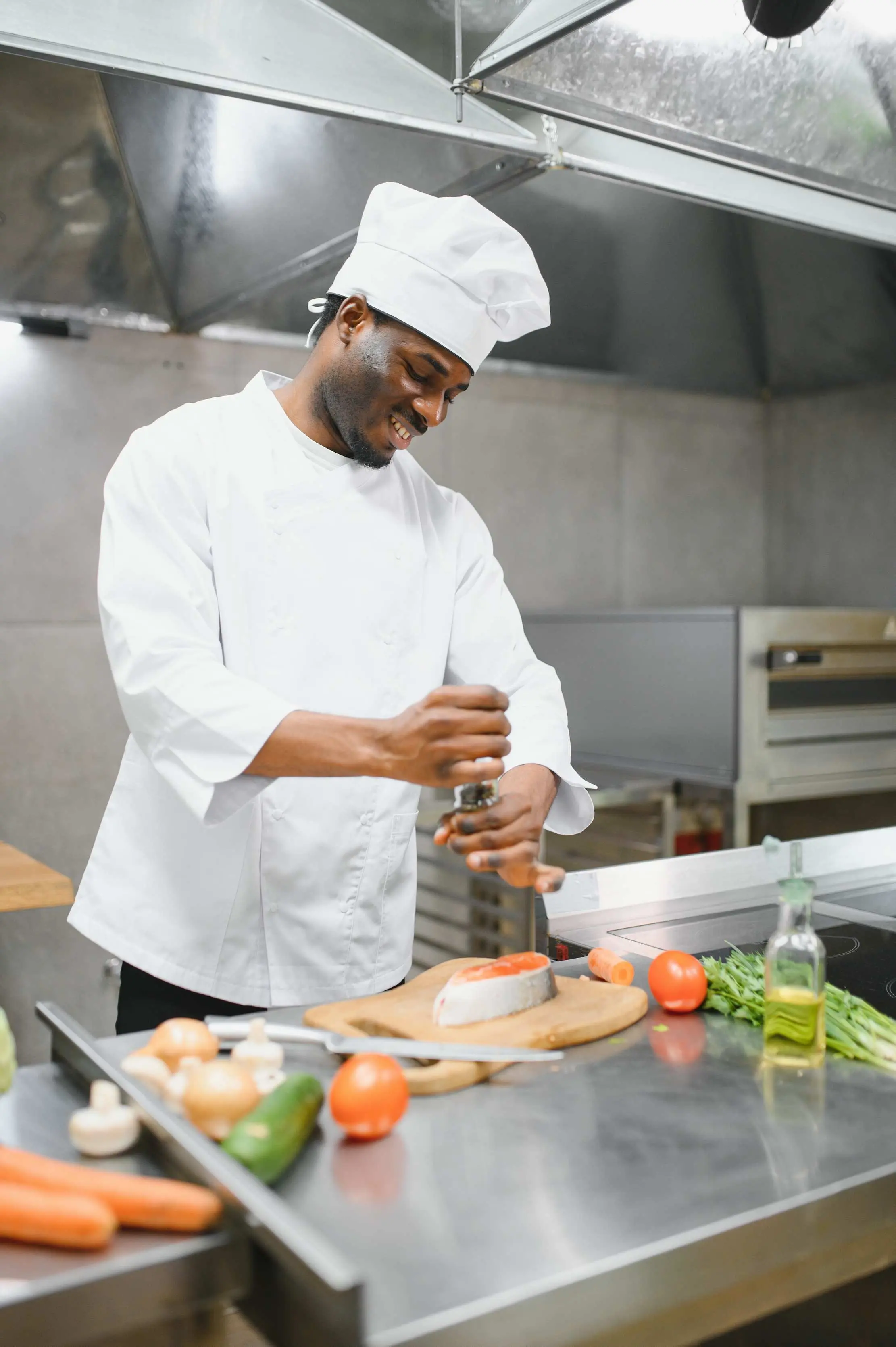 Chef assaisonnant une portion à côté des ingrédients préparés en cuisine