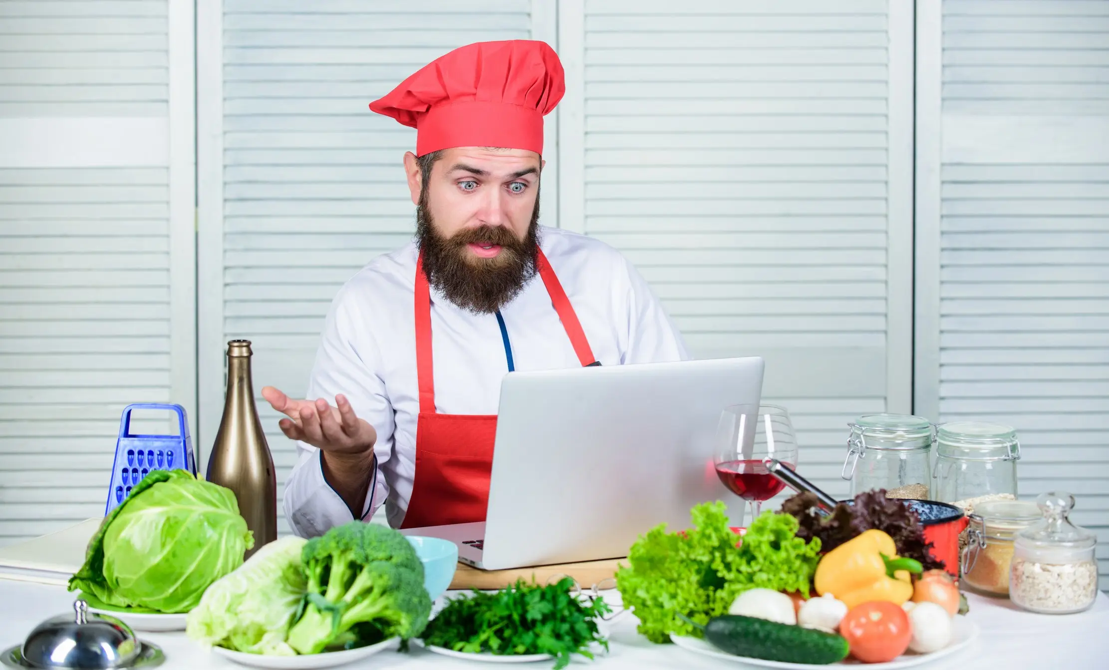 Chef comparant les ingrédients frais avec une fiche recette sur ordinateur