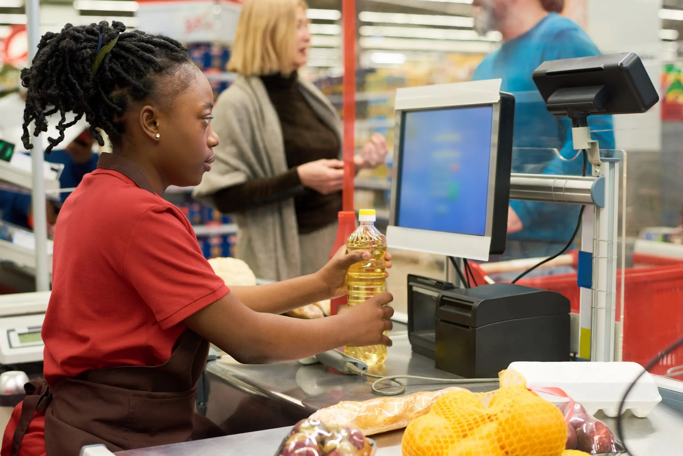 Retail cashier checking product pricing at the counter, representing POS software selection for Ugandan shops