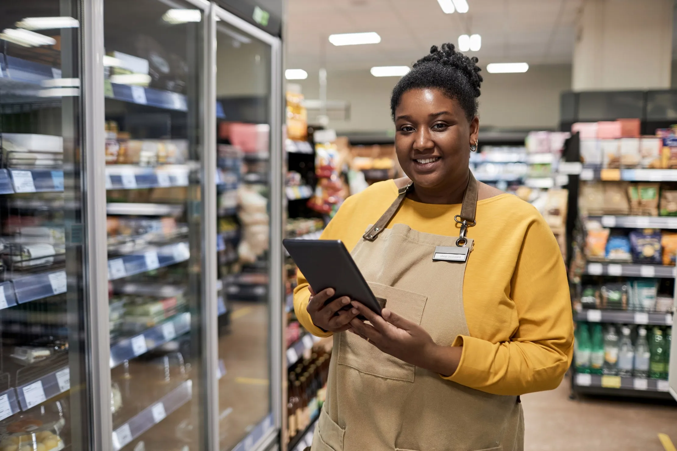 Smiling supermarket worker in a stocked retail aisle after completing a controlled stock routine
